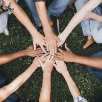 People stacking hands together in the park